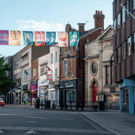 Vibrant street scene in Gloucester, England, with shops, historic buildings, and festive banners, reflecting the city’s blend of heritage and modern life.