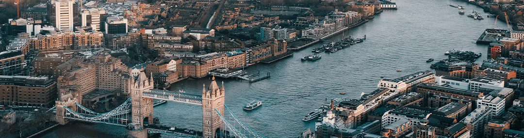 Aerial view of London, showcasing the Thames River and iconic Tower Bridge amidst a mix of modern and historic buildings.