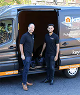 two keytek locksmiths standing outside work van