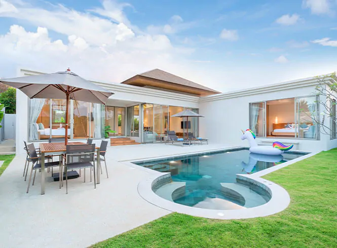 big villa house with lights on, an outdoor table and a pool