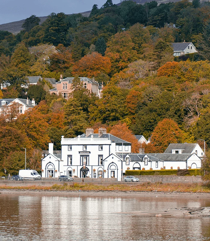 The white Ardencaple Hotel on Gare Loch, against a backdrop of early autumn colour.