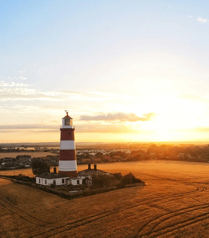 white and black lighthouse on brown sand during sunset