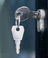 A close-up of a key inserted into a door lock, with a keyring attached, indicating it's ready for entry.